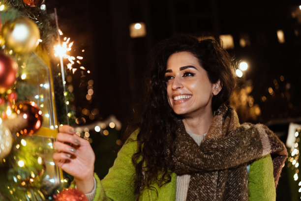 美丽的年轻女子在城市的新年前夜点亮彩灯图片下载