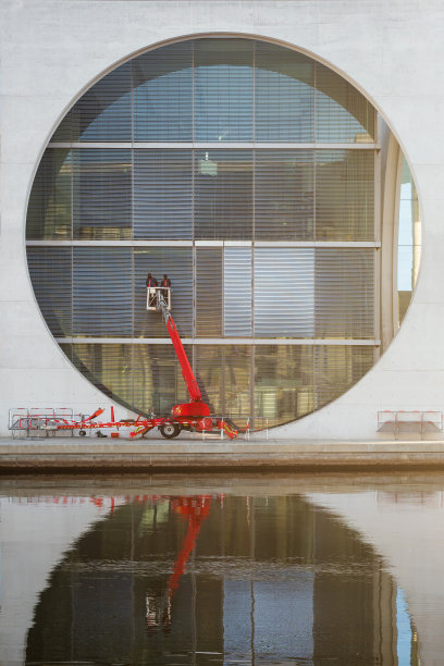 清洁工人使用樱桃采摘机清洁当代办公大楼的玻璃立面。图片下载