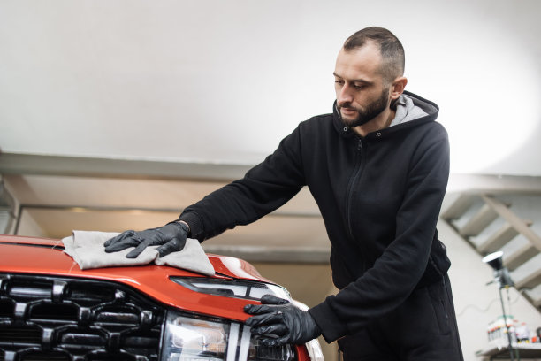 年轻英俊的大胡子洗车工人男子，穿着防护服和手套图片下载