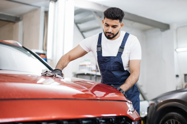 年轻的大胡子男性专业洗车工人戴着黑色橡胶手套，拿着灰色的超细纤维图片下载