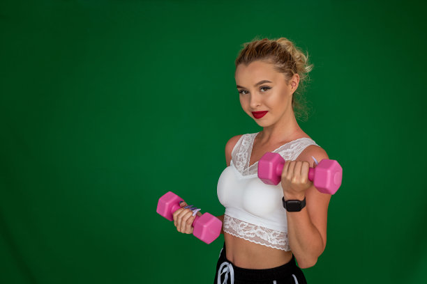 漂亮的年轻女孩穿着漂亮的衣服，手里拿着运动哑铃，放在普通的帆布上。图片下载