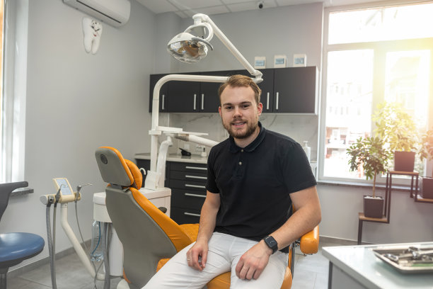 微笑的中年牙医站在他自己的诊所里。图片下载