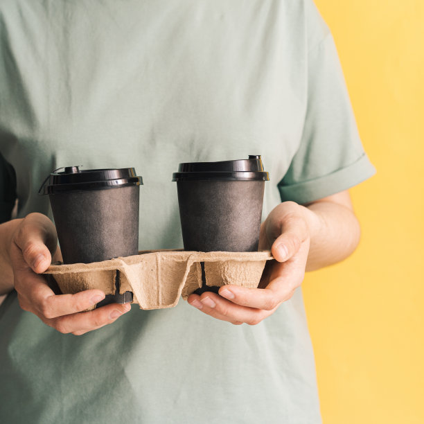 穿着绿色t恤的女孩拿着杯热咖啡，背景是黄色的图片下载