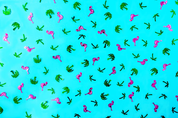 一种由粉红色的火烈鸟和绿色的棕榈树在蓝色背景下组成的闪亮图案。无缝墙纸或背景夏季横幅或广告。平的。图片下载