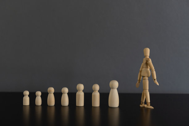 木偶木偶人在木制地板上的黑色桌子上，几个概念木偶领导向前走，代表领导选拔和经营策划。图片下载