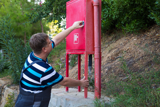 一名工人打开房子附近的消防箱进行检查图片下载