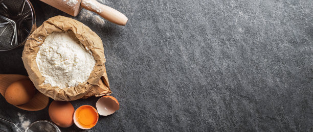 烘烤面团的原料。纸袋面粉和鸡蛋，擀面杖和筛子在黑暗背景与复制空间俯视图图片下载