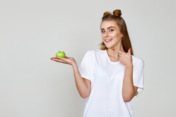 女孩在工作室背景上拿着绿色的苹果图片下载