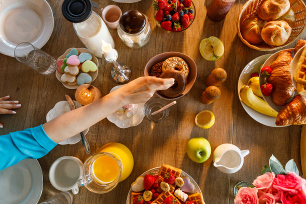 女性伸手去拿餐桌上的巧克力甜甜圈图片下载