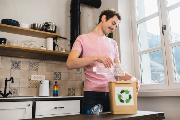 一个年轻人把塑料瓶收集到回收箱里图片下载