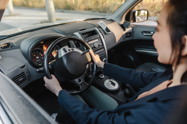 亚洲女人开着车，面带微笑。一个年轻成功快乐的女人正在开车。图片下载