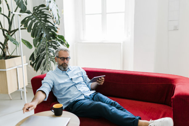 严肃的老人使用平板电脑，喝咖啡，在家里工作图片下载