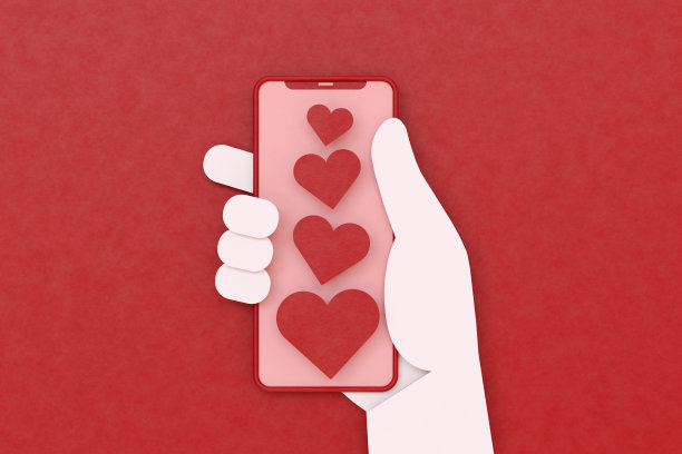手机屏幕上的心形和握着它的手，红色背景，情人节图片下载