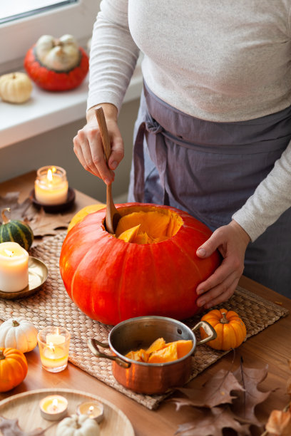 一名妇女在家里雕刻南瓜手工制作南瓜灯，作为万圣节派对的装饰。节日概念，季节性手工装饰。秋色，无脸，特写图片下载