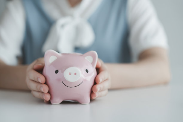 手握粉红储蓄罐，为未来存钱和做预算。企业财务与投资理念。图片下载