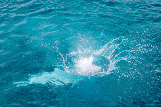 飞溅的蓝色，海水带着泡沫。夏日里自然的水花。蓝色的大海背景与飞溅的水。海上度假的概念。图片下载