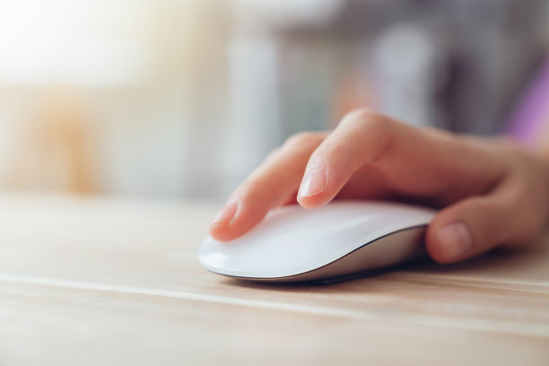 近距离的手使用在白色鼠标和点击办公桌子。图片下载