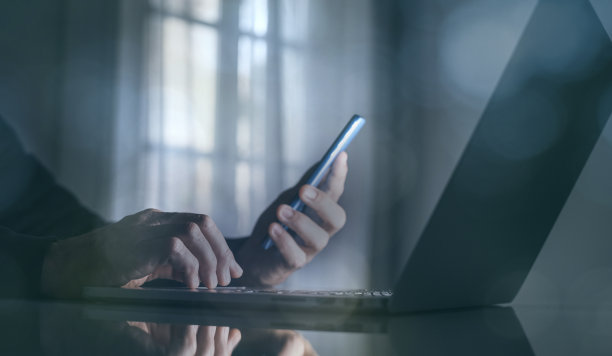 商人在笔记本电脑上用手机工作。技术，商业，金融和市场，概念。图片下载