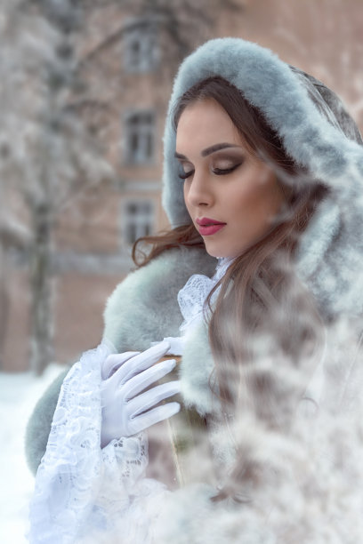 一个美丽的黑发女孩在冬天的公园里阅读一本书图片下载