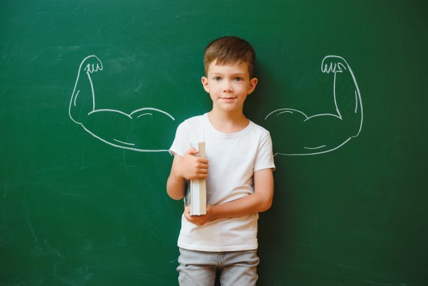 有趣的男孩在教室里的绿色学校董事会附近。小学。回到学校。图片下载