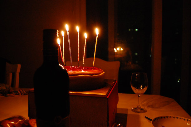 浪漫的生日餐桌，6支蜡烛，奶酪蛋糕，葡萄酒，玻璃杯和晚上的菜图片下载