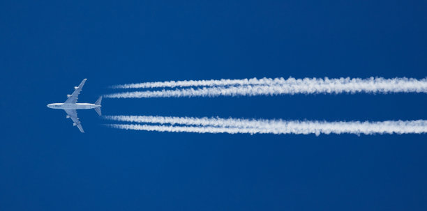 远处有白色的飞机，湛蓝的天空中有尾迹图片下载
