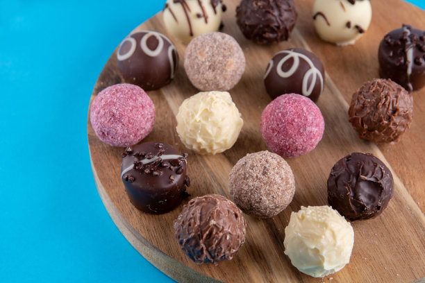 许多美味的巧克力躺在一个圆木板上的照片图片下载