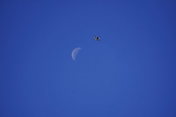 低角度拍摄的mavic无人机和月亮在蓝天图片下载