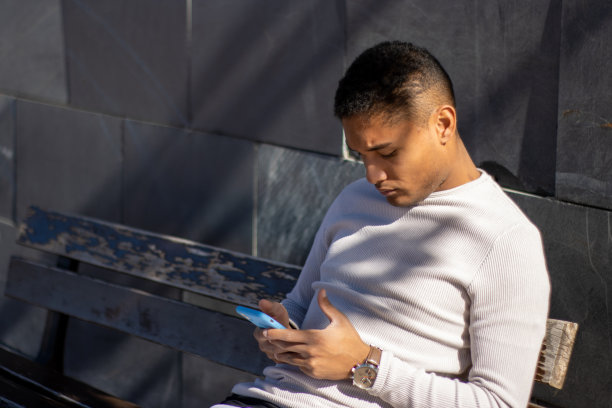 男性坐在长凳上看手机图片下载