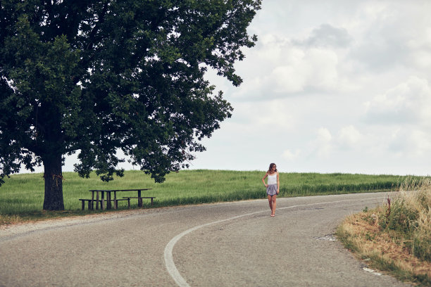 年轻的女人快乐地走在路中间。图片下载