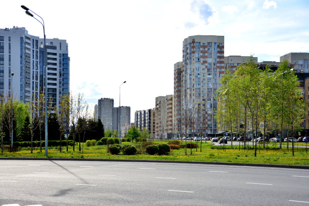 城市街道上的混凝土道路，绿色草坪，树木和摩天大楼为背景图片下载