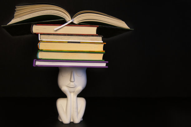 陶瓷思维小雕像，黑色背景上有很多书图片下载