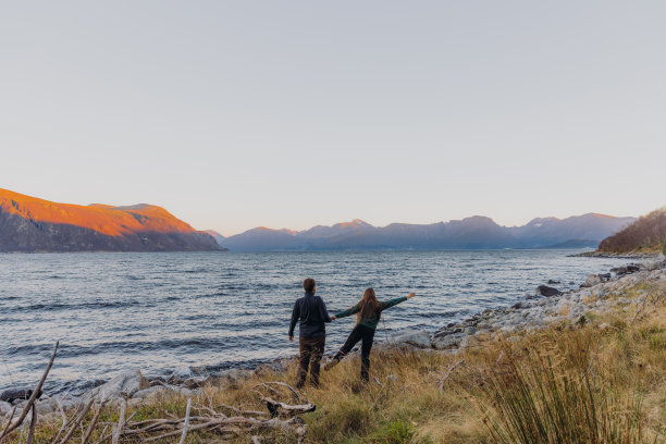 一个女人和一个男人在海边凝视着快乐的日落时分图片下载
