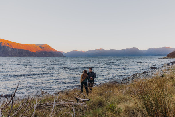 一个女人和一个男人在海边凝视着快乐的日落时分图片下载