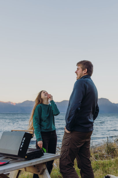 一个女人和一个男人在海边野餐，凝视着快乐的日落时分图片下载
