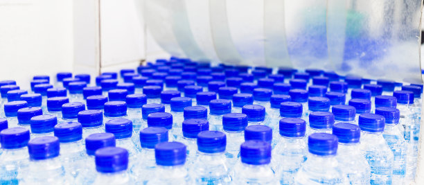 很多水瓶。蓝色瓶盖的瓶子。装瓶厂-水装瓶生产线，用于加工和装瓶饮用水。图片下载