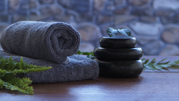 水疗中心的概念。美丽的温泉产品的俯视图。热石头，毛巾，按摩油图片下载