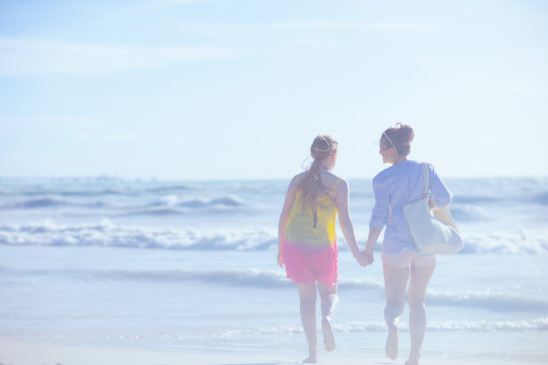 从后面看，现代母亲和孩子在海滩上奔跑图片下载