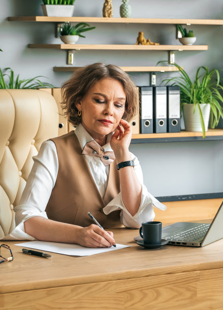 自信时尚成熟中年老年妇女在办公室。办公场所带笔记本电脑，使用手机通话。总经理、首席执行官。资深女商人，60年代西装革履的女士，高级商业领袖。企业家的事业。银行会计图片下载