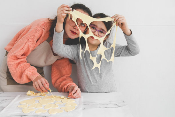两个白人女孩:一个在做面团，另一个在她的脸上刻着一颗心。图片下载