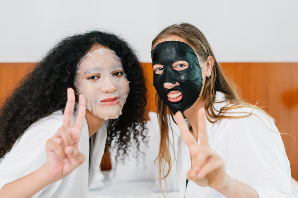 微笑的女孩预防皱纹，照顾皮肤，两个年轻的女人在脸上涂抹保湿和美容面膜与朋友图片下载