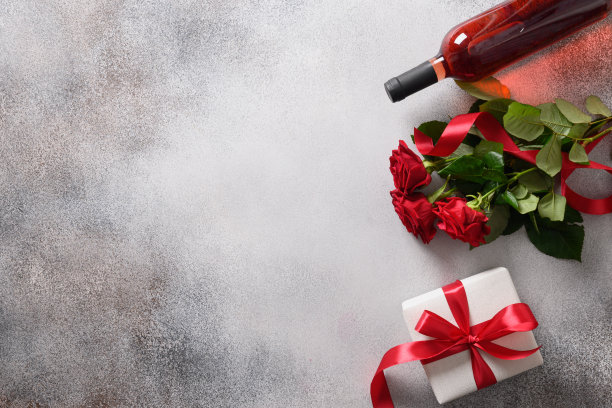 情人节卡片，有红酒、礼物和灰色背景的红玫瑰。图片下载