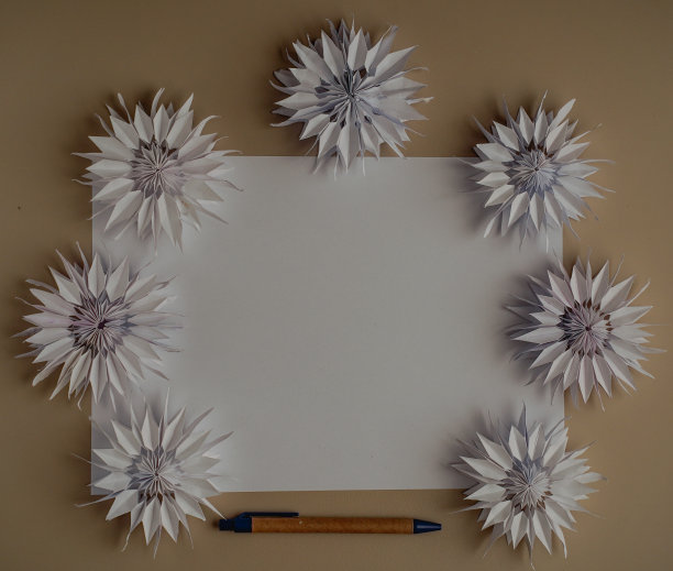 文本复制空间。横放一张纸，一支笔，7个折纸花特写俯视图DIY。新年圣诞生日装饰。模糊的背景图片下载