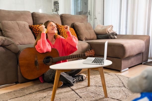 一位女士在家里学习弹吉他，庆祝她弹得很好图片下载