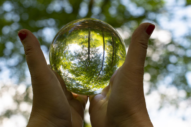 女性用红色指甲握着发光的水晶球，将自然包裹在里面，表现出女性对自然的关爱和气候图片下载