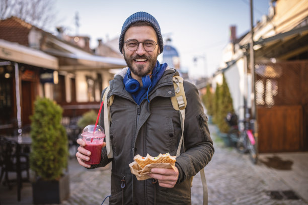 一个人走在城市里，吃着三明治图片下载