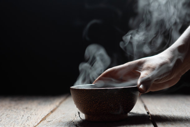 蒸汽的热汤与烟木碗在黑暗的背景。有选择性的重点。热食概念图片下载