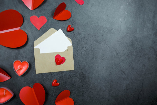 横幅。红心，一个信封，一张白纸，黑色背景上有复制空间。情人节节日问候的概念。图片下载