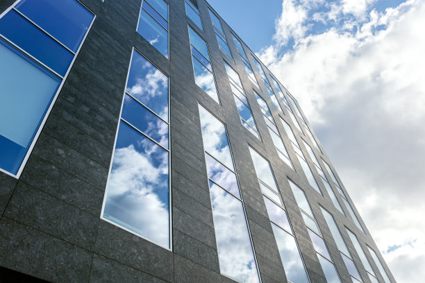 现代办公大楼。玻璃立面有多云的天空反射。当代城市建筑。图片下载