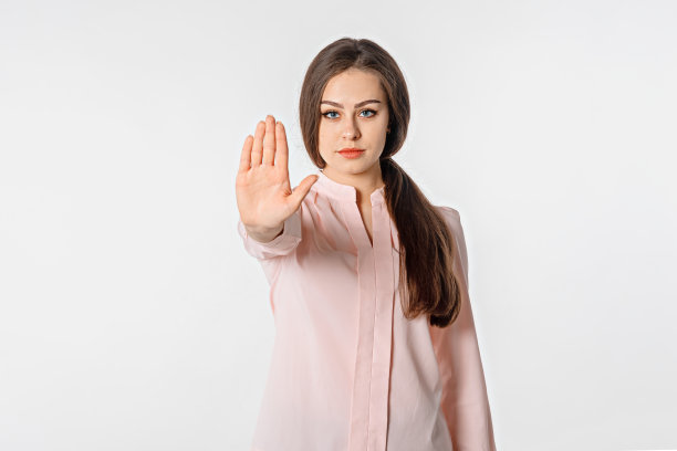 阻止它。社会距离。年轻女子站在白色背景下，用手做停止手势，说“不”。严肃的长发女孩不赞成史密斯、禁止、忌讳手势图片下载